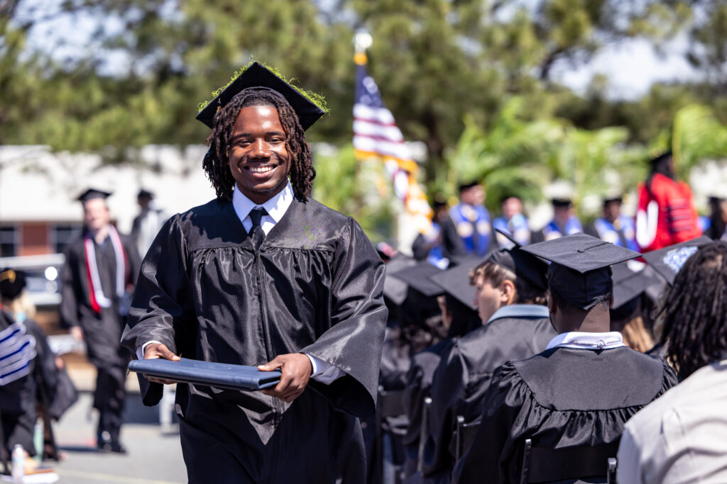 South Piedmont student walking back to his seat after receiving his diploma, with a big smile on his face.