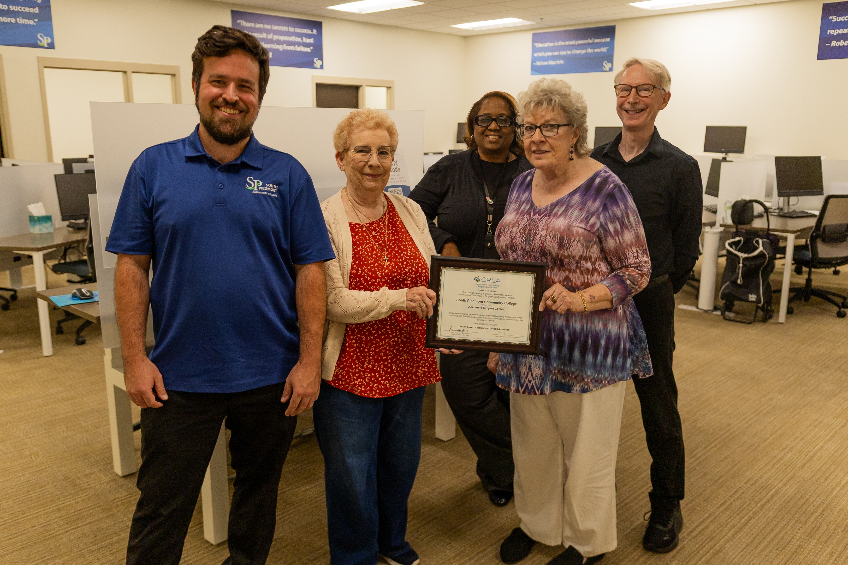 A group of people standing in a computer lab holding a certificate.