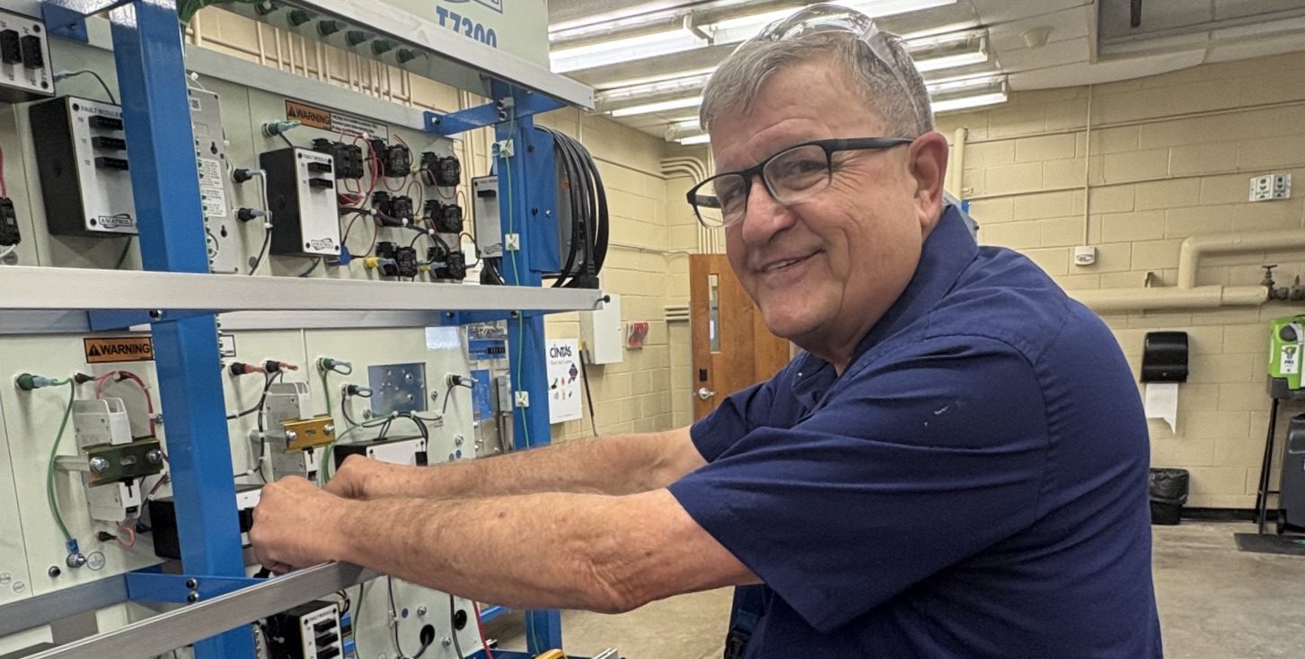 A man in a blue shirt working on HVAC equipment.