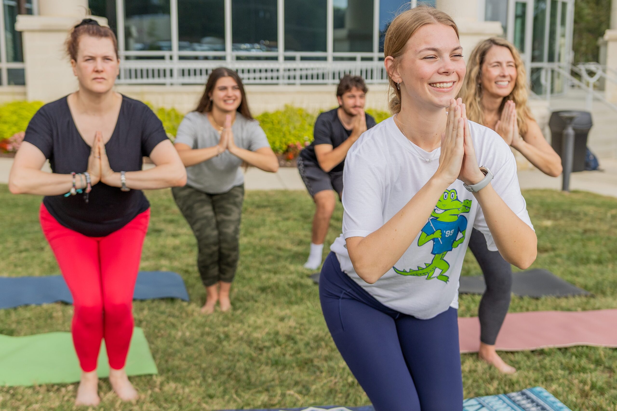 Groups of people practice yoga outside of South Piedmont's OCH Main building.