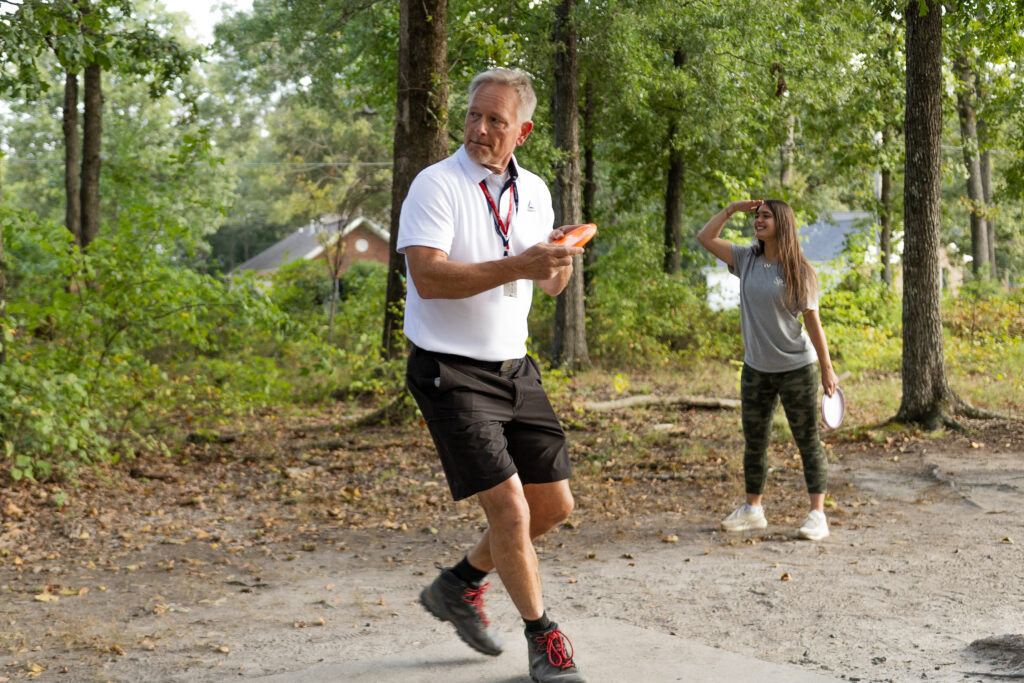 Two people try their luck at disc golf in an outdoor setting.
