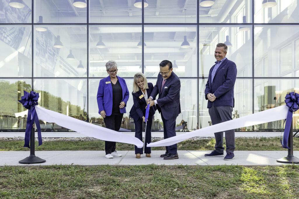 A group of people cutting a ribbon in front of a new building.