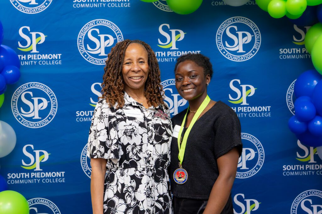 Mary Cornelia with a student standing in front of South Piedmont custom wall banner.