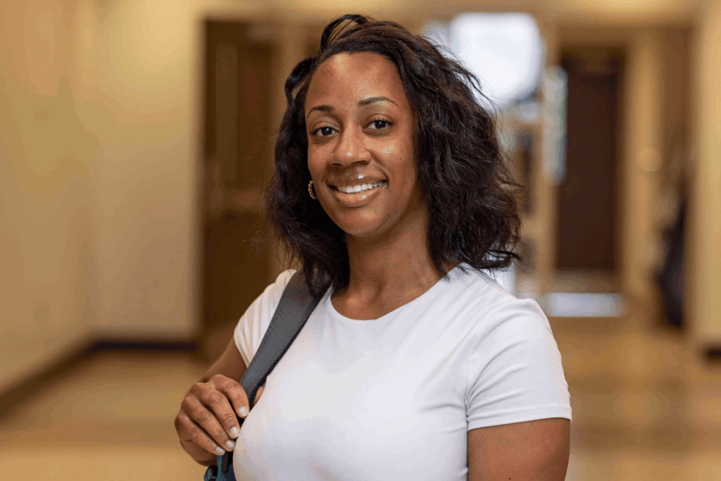 Woman student with her backpack, smiling at the camera.